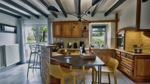 Une cuisine moderne avec des meubles en bois, un îlot central et un coin repas doté de chaises jaunes.