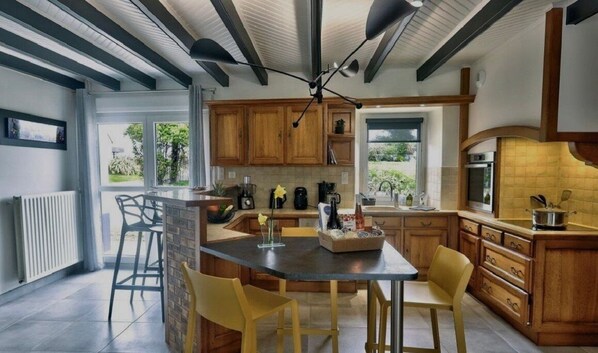 A modern kitchen with wooden cabinets, a central island, and a dining area with yellow chairs.