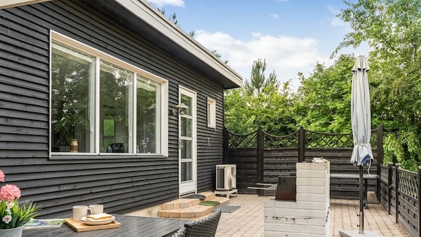 Un espace patio aménagé avec une table et des chaises, un barbecue et un parasol.
