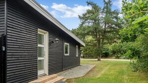 Un bâtiment d’un seul étage, à l’extérieur sombre, avec une porte d’entrée et un petit porche.