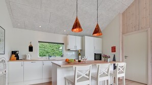 Eine moderne Küche mit weißen Schränken, einer Holztischinsel und Pendelleuchten.