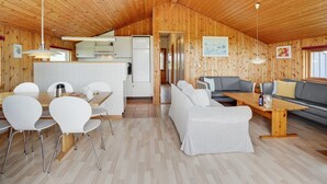 Una cabaña de madera espaciosa con comedor, cocina y sala de estar.