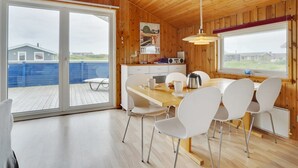 Un interior de madera con comedor, ventanas amplias y vista al exterior.