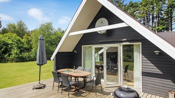 A modern house with a deck, a dining area, and a barbecue grill.