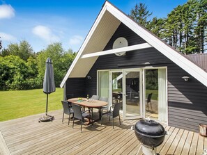 Ett modernt hus med en terrass, en matplats och en grill.