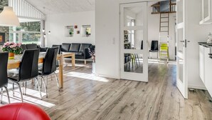 Un espace de vie moderne comprenant un coin repas, un canapé en cuir noir et un escalier menant à un niveau supérieur.