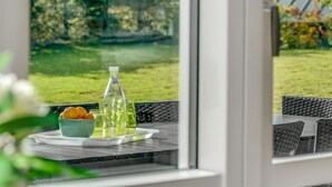Un coin repas avec une table dressée pour deux personnes, agrémenté d’un saladier de fruits, d’une bouteille et de verres.