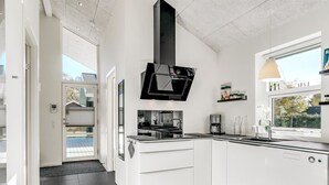 Une cuisine moderne avec des armoires blanches, une hotte noire et une fenêtre donnant sur l’extérieur.