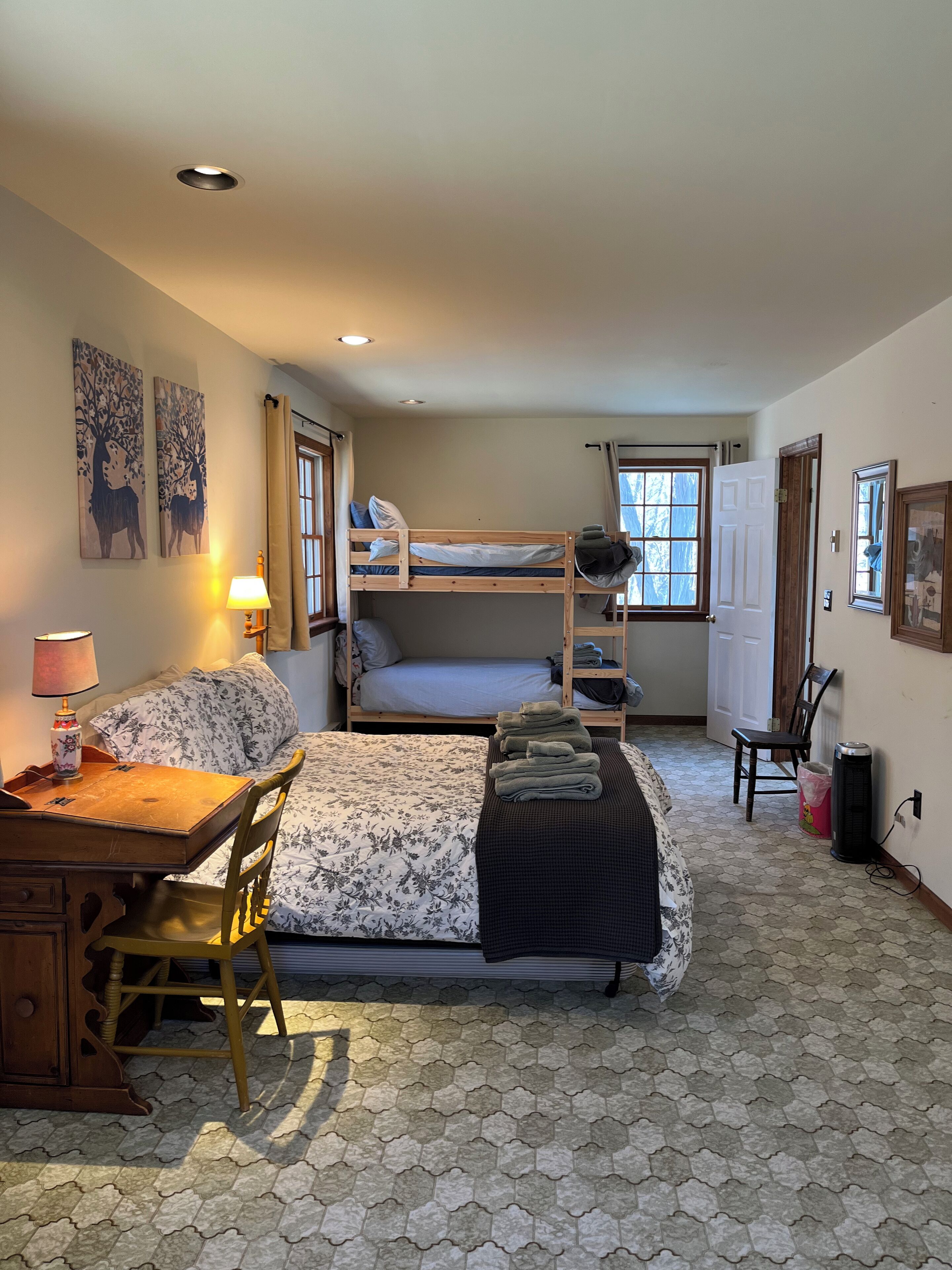 A compact room with bunk beds, a desk, a chair, and a lamp.
