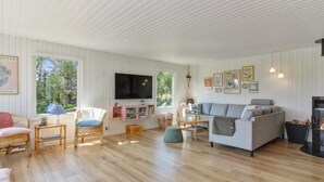 Un salón amplio con un televisor grande, asientos cómodos y una chimenea.