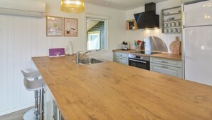 Cocina con encimera de madera, electrodomésticos de acero inoxidable e iluminación colgante.