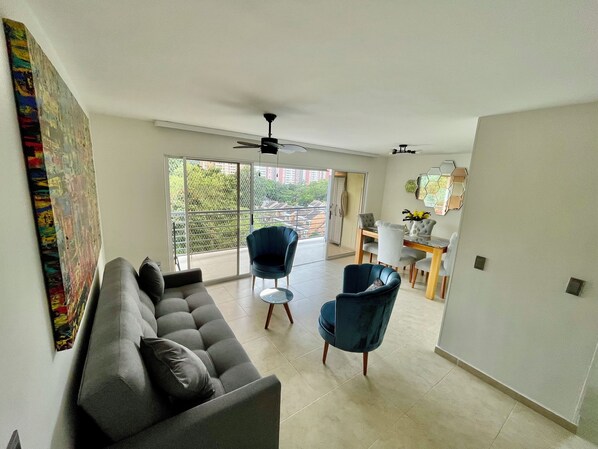 A modern living room with a sofa, two armchairs, a dining table, and a ceiling fan. - Beautiful Apartment Close to Campestre Club in Bucaramanga (Floridablanca)