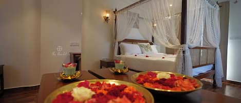 A hotel room with a four-poster bed, a bedside table with a lamp, and a nightstand.