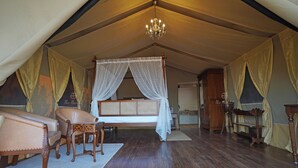 A tented room with a bed, a sofa, a chandelier, and a welcome mat. - The Hamlet (Kondapur)