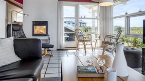 Un salon moderne doté d’une cheminée, de sièges confortables et de grandes fenêtres offrant une vue sur l’extérieur.