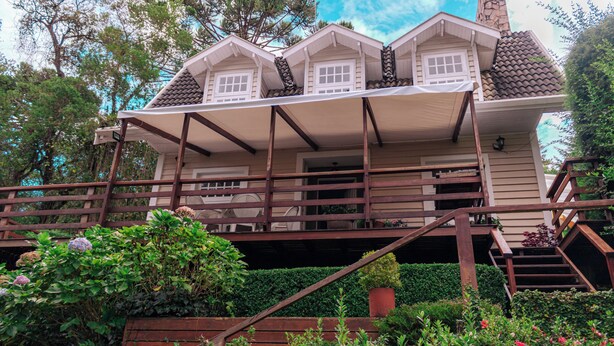 A two-story house with a covered porch and wooden stairs. - Casa do Bosque Campos do Jordão (Campos do Jordão)