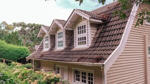 A two-story house with a sloped roof and multiple windows. - Casa do Bosque Campos do Jordão (Campos do Jordão)
