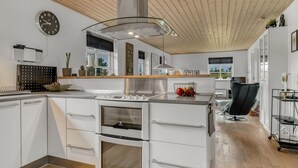 A modern kitchen with white cabinetry, a built-in oven, and a stainless steel range hood.