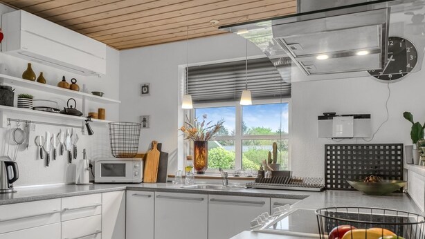 A modern kitchen with white cabinetry, a microwave, a sink, and a fruit bowl on the counter.