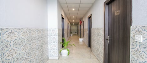 A hallway with patterned walls, a tiled floor, and doors on both sides.