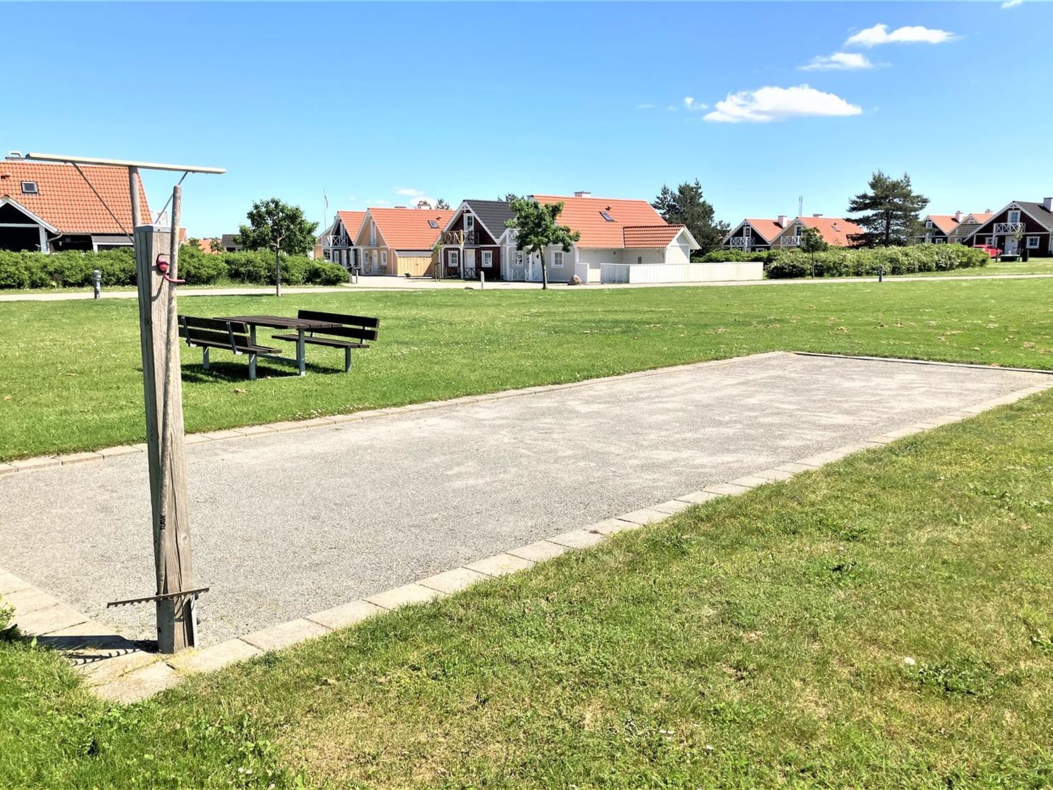 A park with a paved area, benches, and houses in the background.