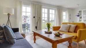 Un salon comprenant un canapé, un fauteuil jaune, une table basse en bois et un lampadaire.