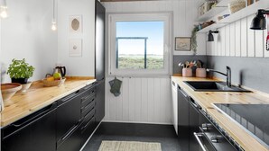 Una cocina compacta con mostradores de madera, estufa integrada y ventana con vista al exterior.