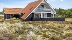 Una casa moderna con techo inclinado, ventanas amplias y una terraza de madera.