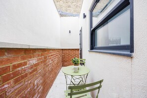 Enjoy a peaceful retreat in this serene outdoor space with a round table, green chair, and potted plant.