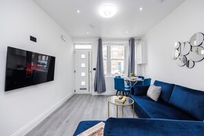 Relax in this stylish living room with a large flat-screen TV, comfortable sofa, and dining area.