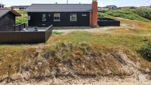 A modern house with a black exterior, a brick chimney, and a small deck with outdoor furniture. - "Terhi" - 200m from the sea by Interhome (Fanø)