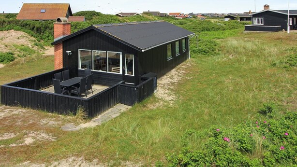 A modern black building with a flat roof and large windows, surrounded by grassy dunes and other houses. - "Terhi" - 200m from the sea by Interhome (Fanø)