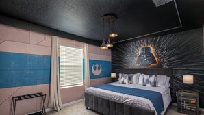 A bedroom with a bed, bedside lamps, a wall art of Darth Vader, and a window with curtains.