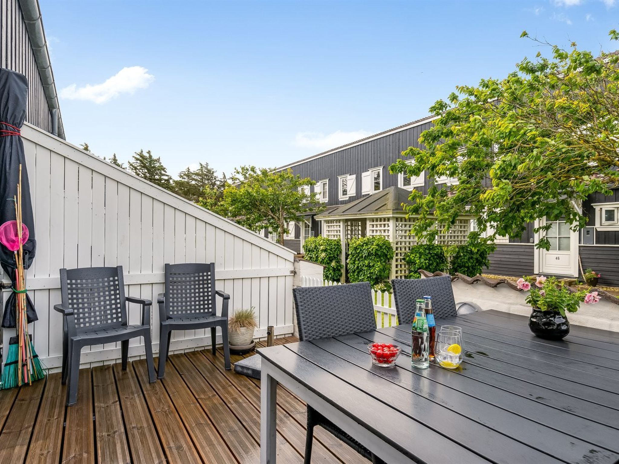 A wooden deck with two black chairs and a table, a potted plant, and a bottle of water.
