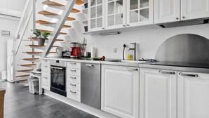 Eine moderne Küche mit weißen Schränken, einer Edelstahl-Spüle und einer Holztreppe.