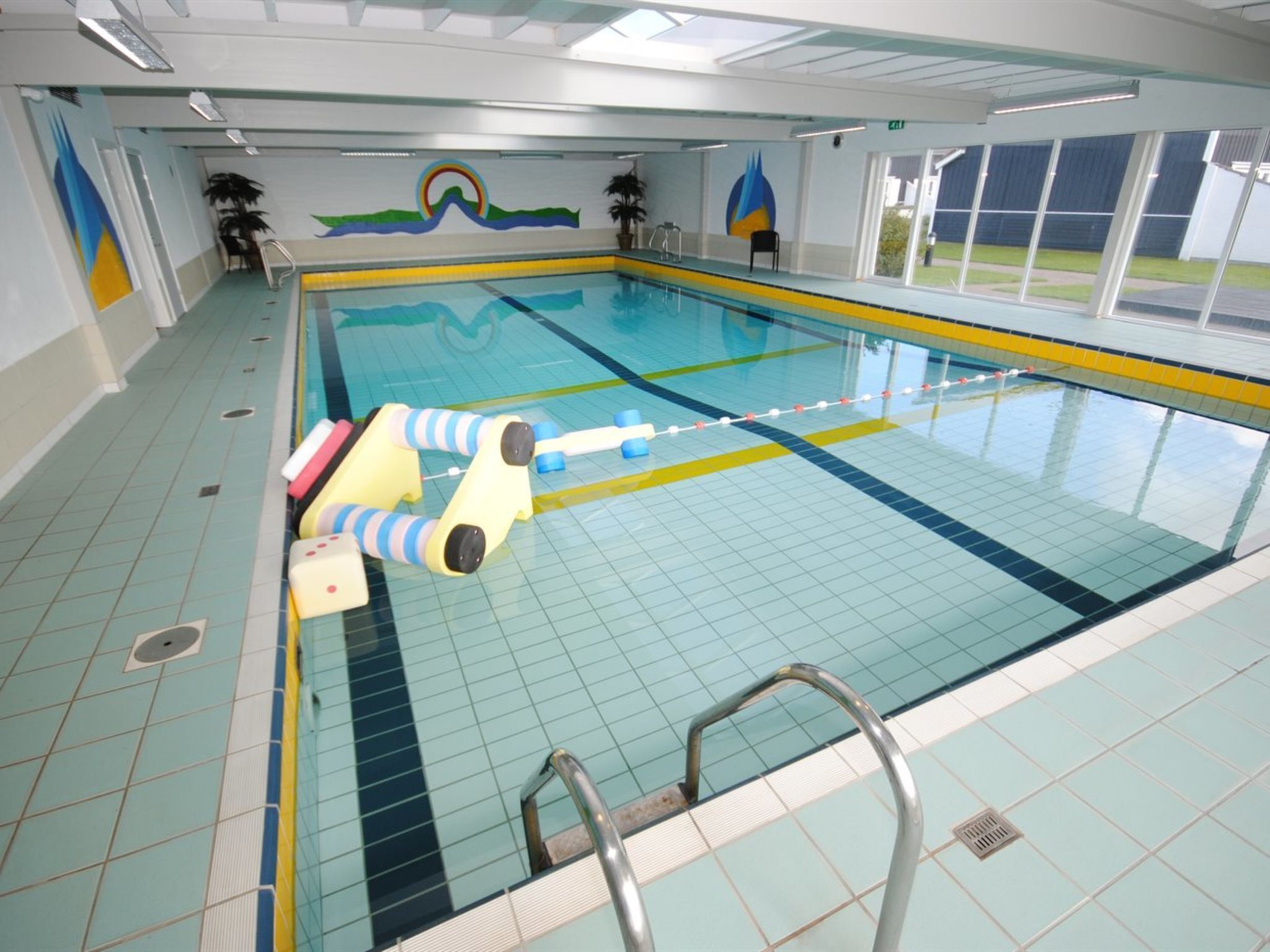 Una piscina coperta con corsie delimitate, un trampolino di partenza e una sedia per il bagnino.