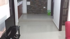 A hallway with a stone wall, a TV stand, and a red chair.