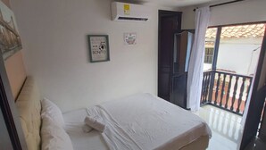 A bedroom with a bed, a wall-mounted air conditioner, and a door leading to a balcony.