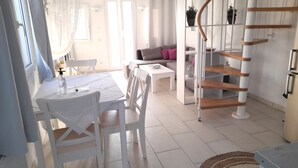 A bright, modern living space with a dining area, a staircase, and a kitchen. - atlantis villa - sea paradise (Santorini)
