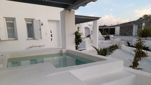 A modern outdoor pool area with a white pool, steps leading into the water, and a covered seating area with white furniture. - atlantis villa - sea paradise (Santorini)