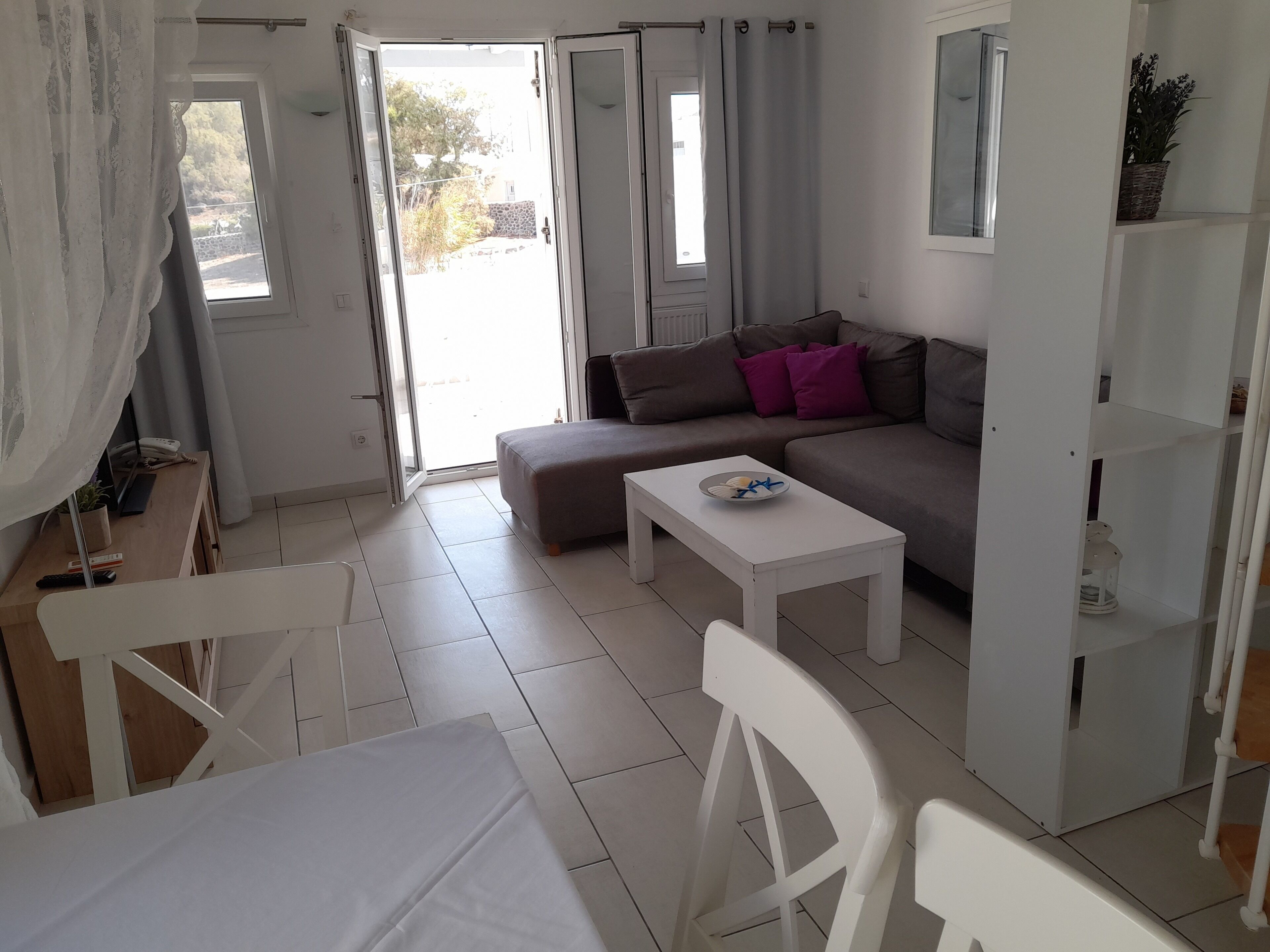 A modern living room with a sofa, a coffee table, and a dining area with a table and chairs.