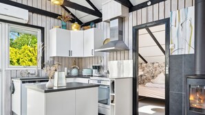 Een moderne keuken met een centraal eiland, inbouwapparatuur en een houtkachel.