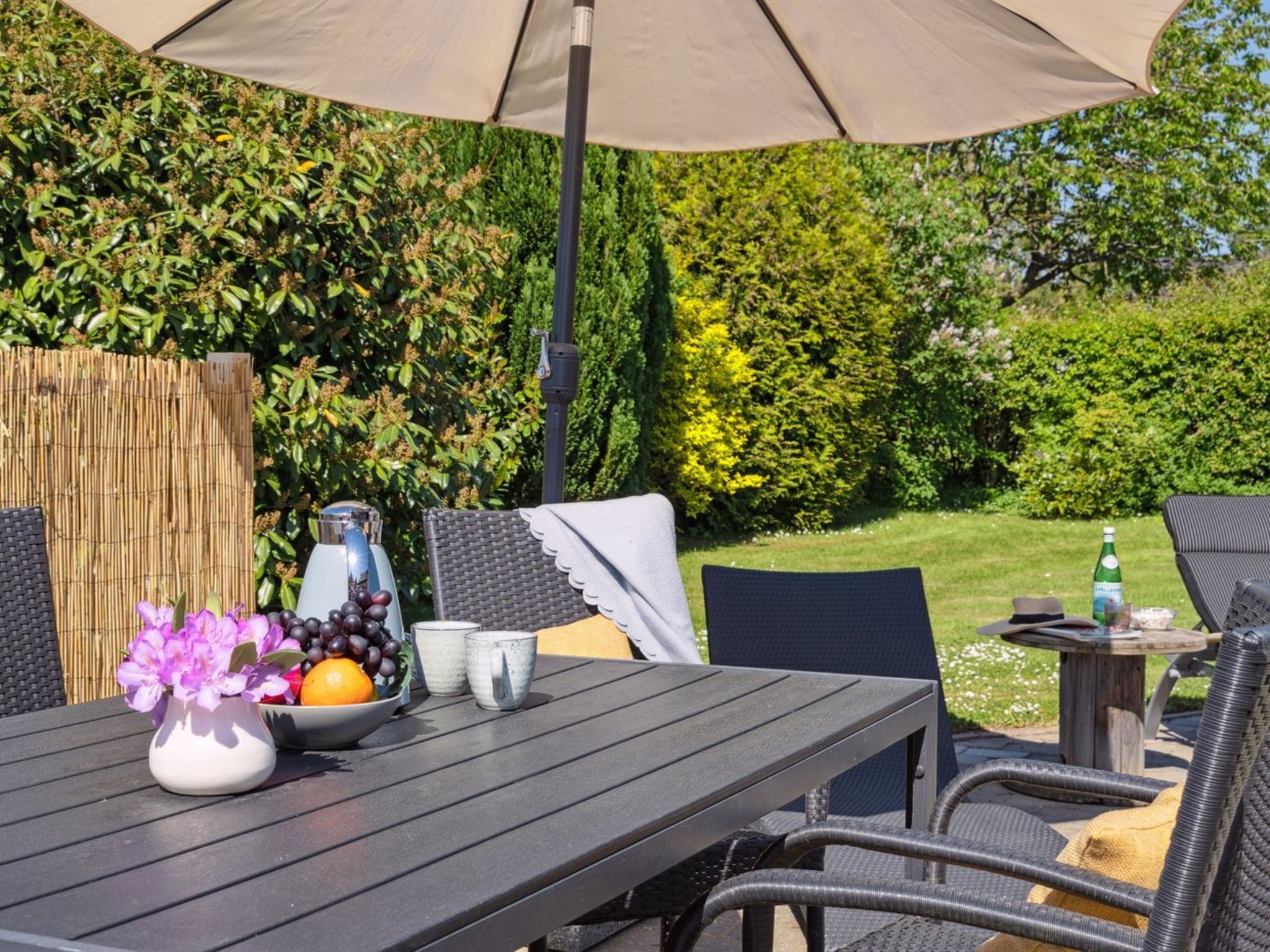 An outdoor patio with a table, chairs, and an umbrella.