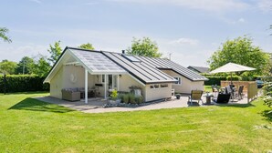 Een huis met een overdekte patio, een tuin en een dak voorzien van zonnepanelen.