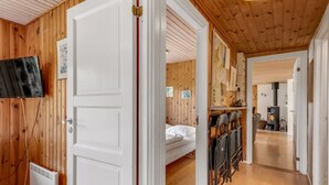 A wooden-paneled room with a bed, a TV mounted on the wall, and a white door.