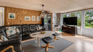 A modern living room with a black leather sofa, a round coffee table, and a TV.
