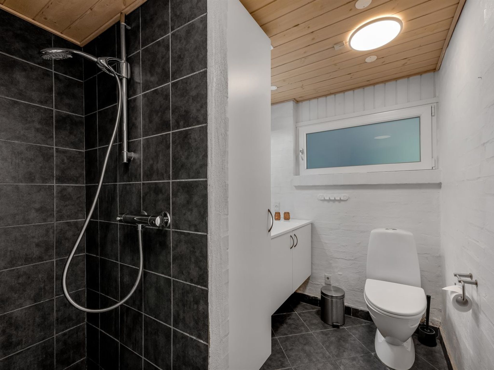 Een moderne badkamer met douche, toilet en wastafel.