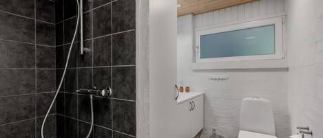 Een moderne badkamer met douche, toilet en wastafel.