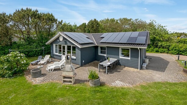 A house with a sloped roof, a patio with outdoor seating, and a garden area.
