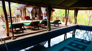 A pool area with lounge chairs and a covered seating area.